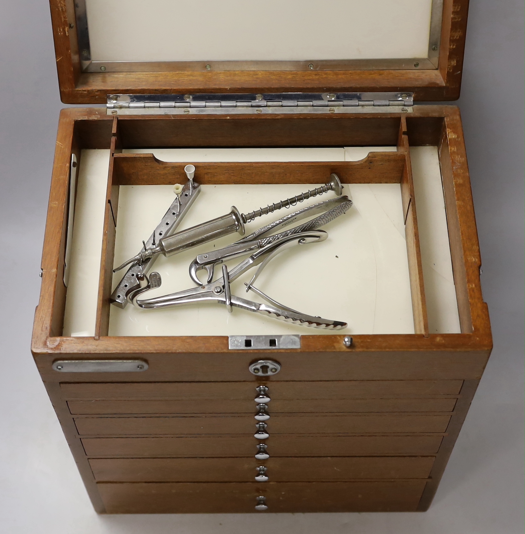 An early 20th century teak dental cabinet, glass lined drawers with chrome fittings, some dental implements included, dimensions, 40 x 33 x 23cm